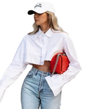 Woman wearing a white cap, white cropped shirt, blue jeans, and holding a red bag 