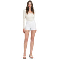 Woman wearing a white top and shorts on a plain background