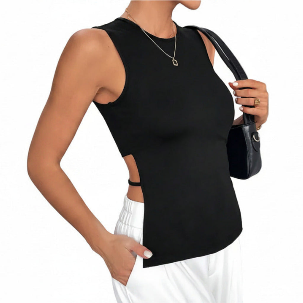 Woman wearing a black sleeveless top with a cutout design, holding a black handbag against a white background.