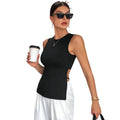Woman in black sleeveless top and white pants holding a coffee cup against a plain background