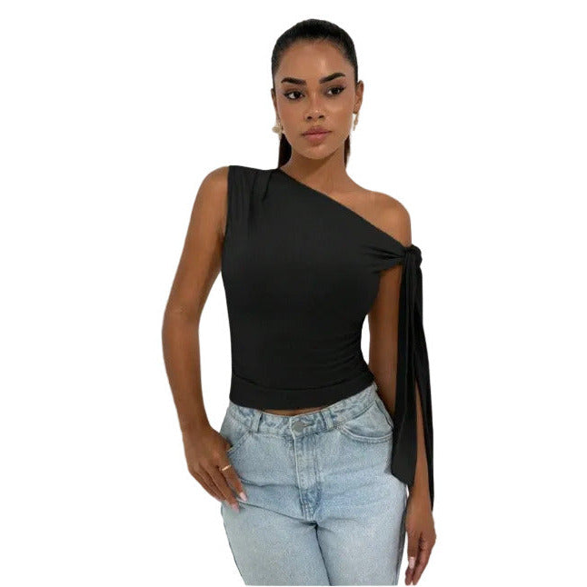 Woman wearing a black one-shoulder top and light blue jeans against a white background
