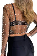 Sheer top with pearl embellishments and black pants on a plain background