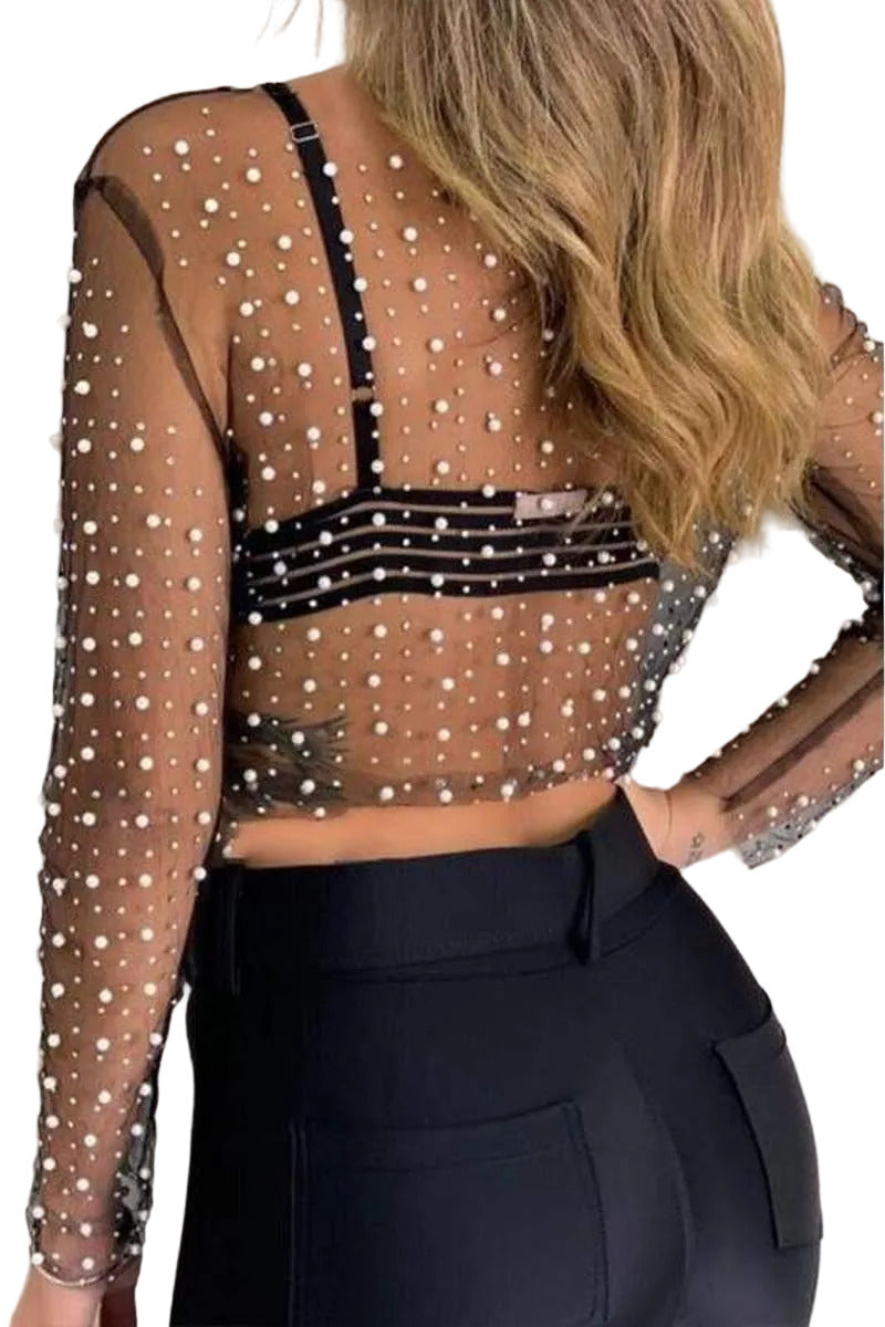 Sheer top with pearl embellishments and black pants on a plain background
