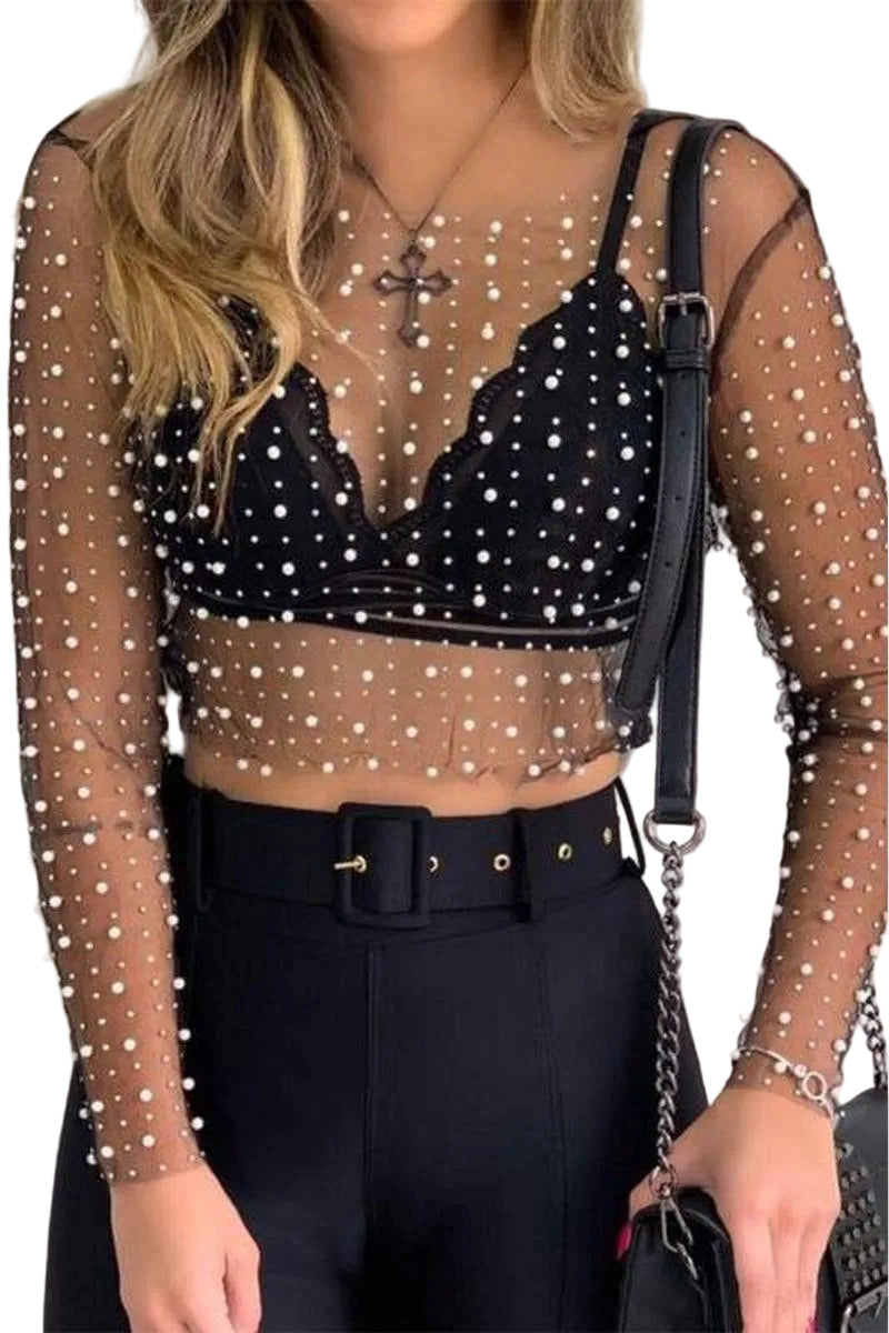 Person wearing a black sheer top with white embellishments and black pants.