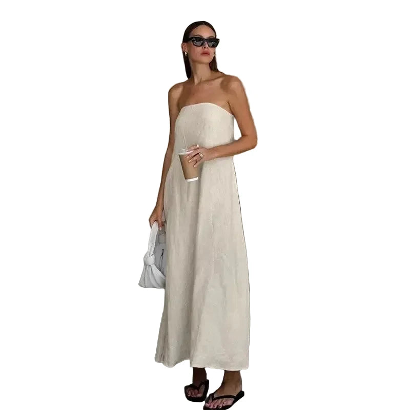 Woman in a strapless beige dress standing against a plain wall.