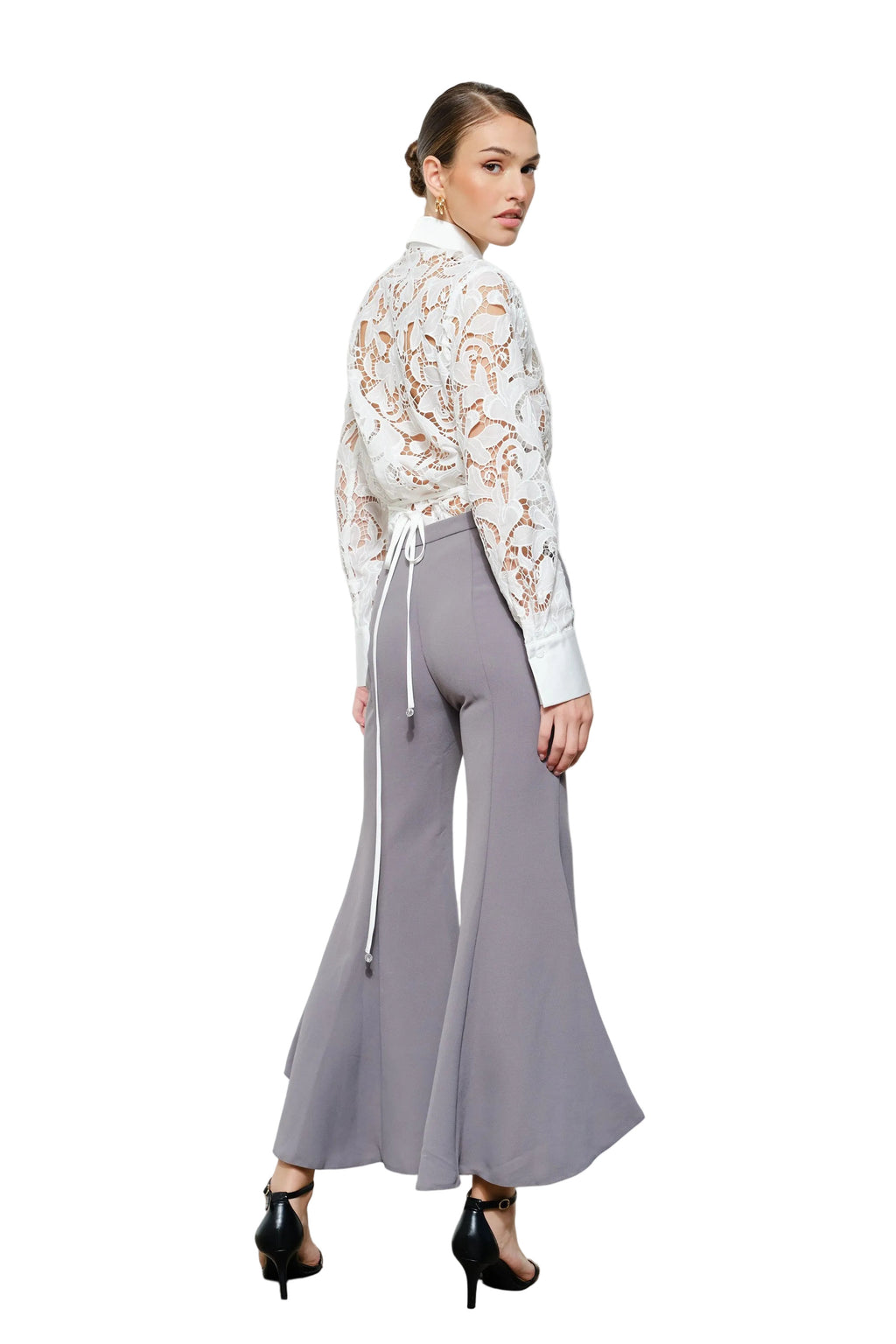 Woman wearing a floral blouse and gray wide-leg pants on a white background