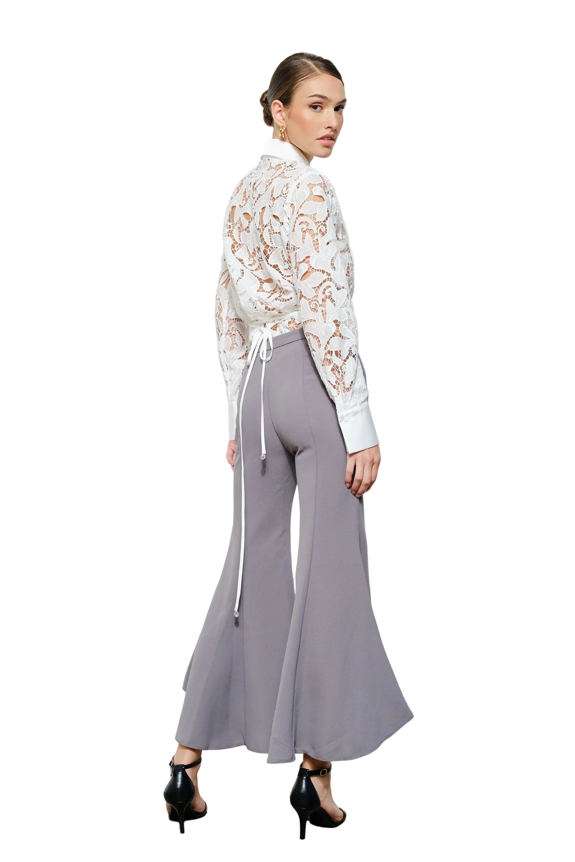 Woman wearing a floral blouse and gray wide-leg pants on a white background
