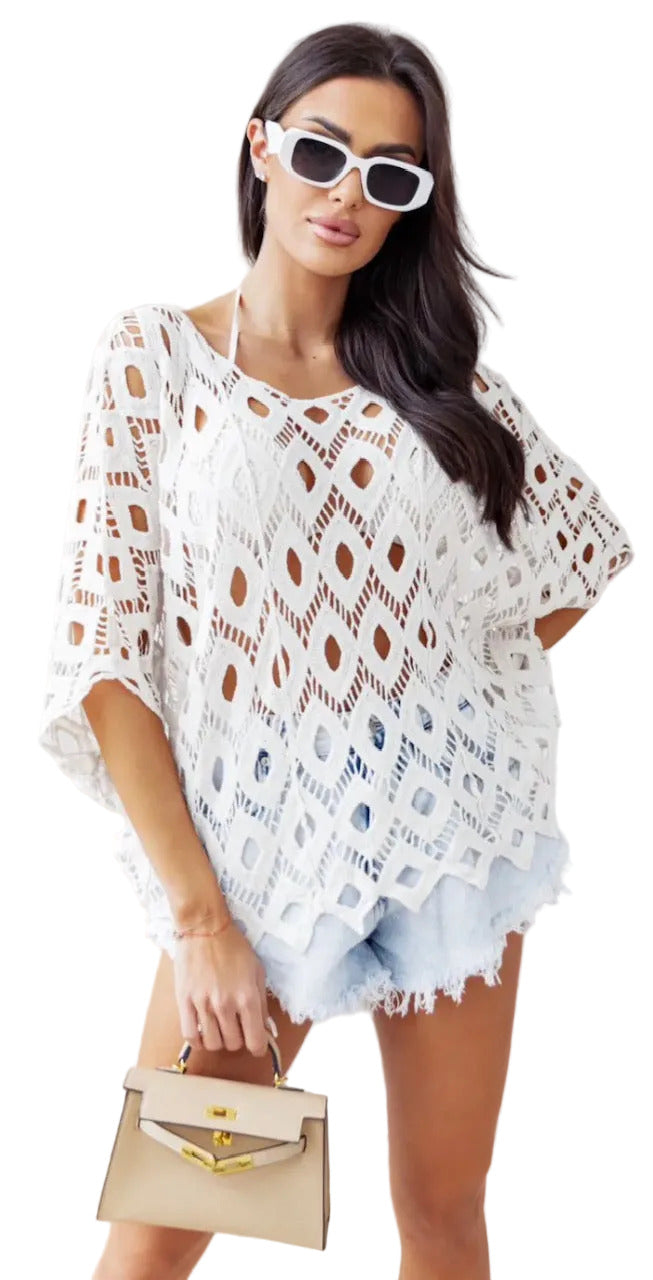Woman wearing a white crochet cover-up and sunglasses, holding a beige handbag.