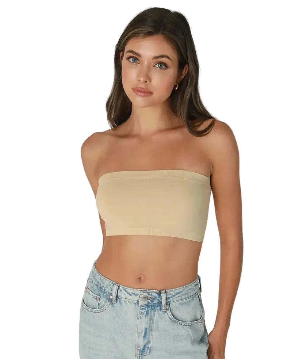 Woman wearing a beige strapless top and light blue jeans on a plain background