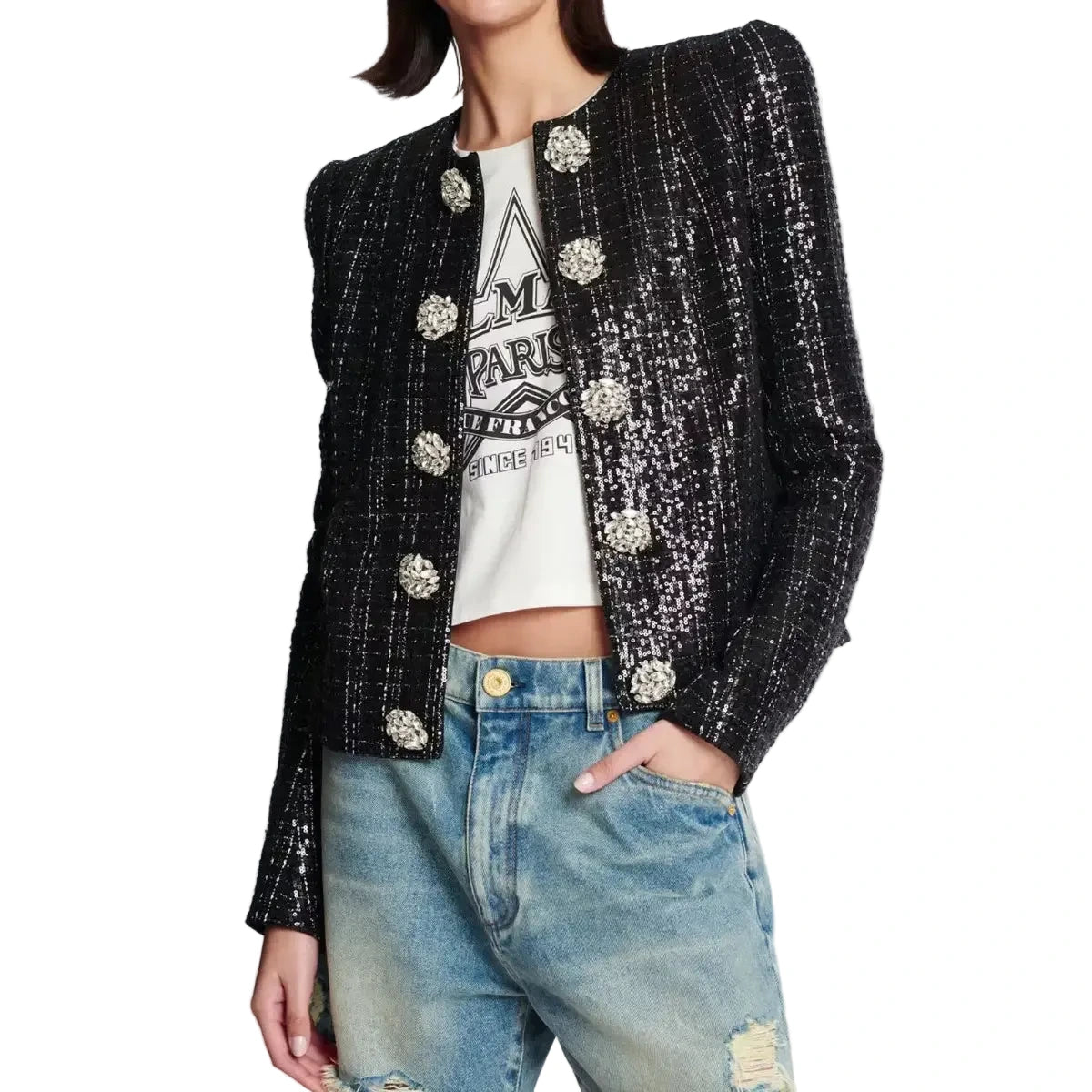 Person wearing a black sequin jacket over a white graphic t-shirt and blue jeans on a light gray background