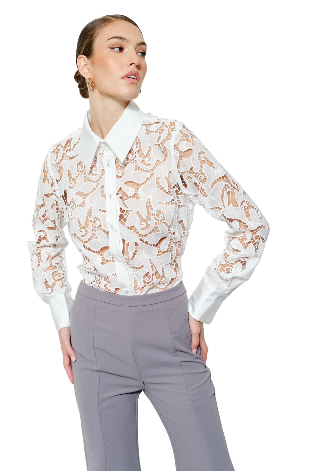 Woman wearing a white lace blouse with long sleeves and gray pants on a white background