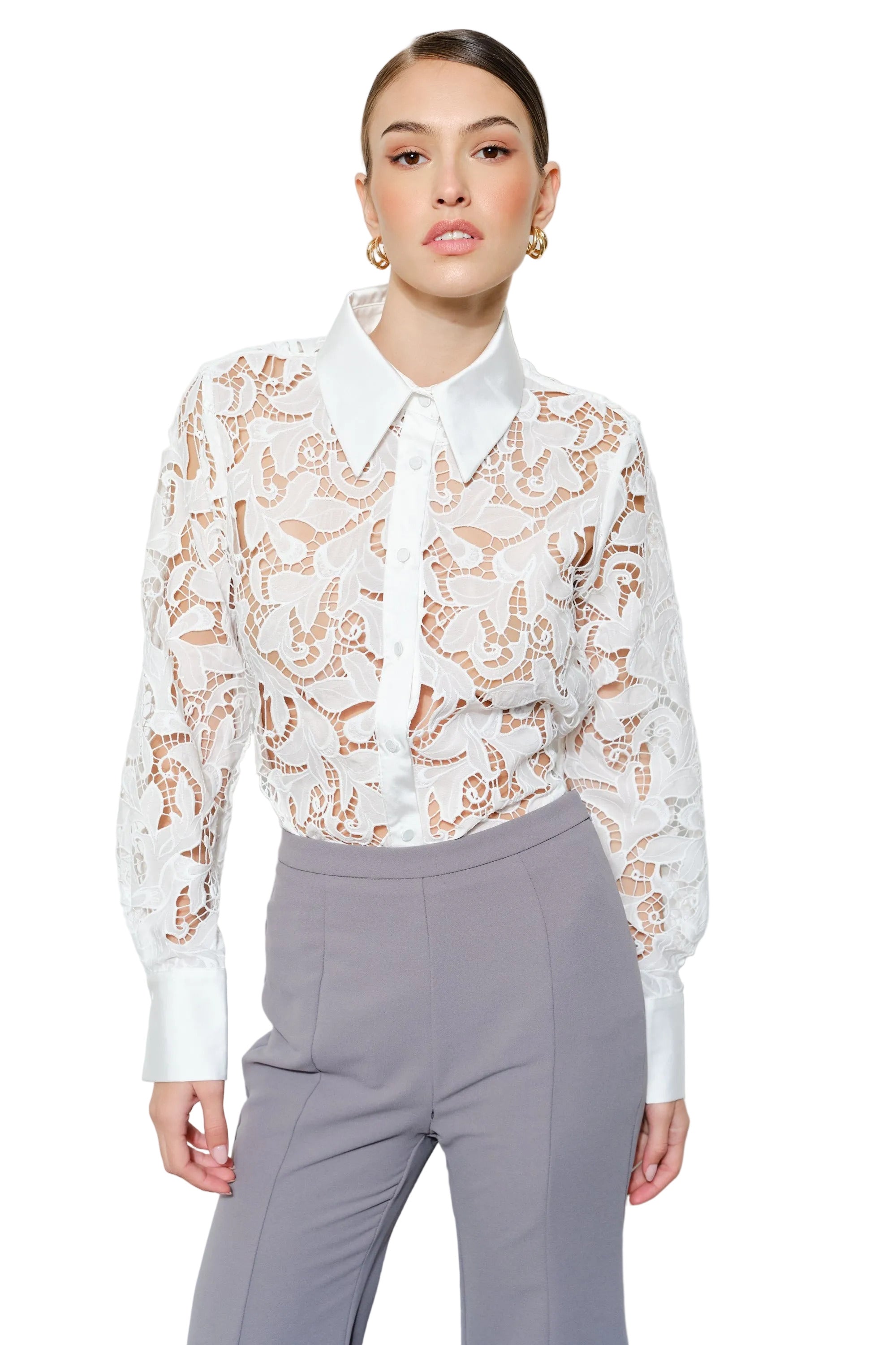 Woman wearing a white blouse with a floral pattern and gray pants on a white background