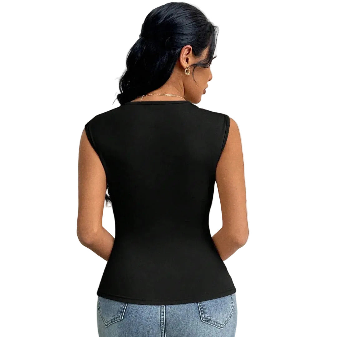 Person wearing a black sleeveless top and blue jeans against a textured white wall.