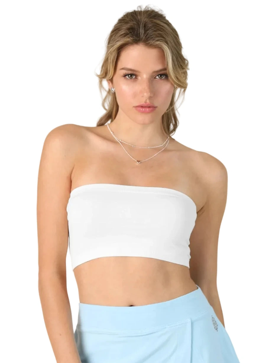 Woman wearing a white strapless top and light blue skirt on a plain background